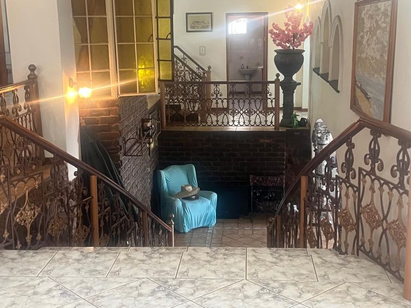 Entrance foyer featuring decorative wrought iron balustrades, exposed brick accents, and tiled flooring with a split-level layout.