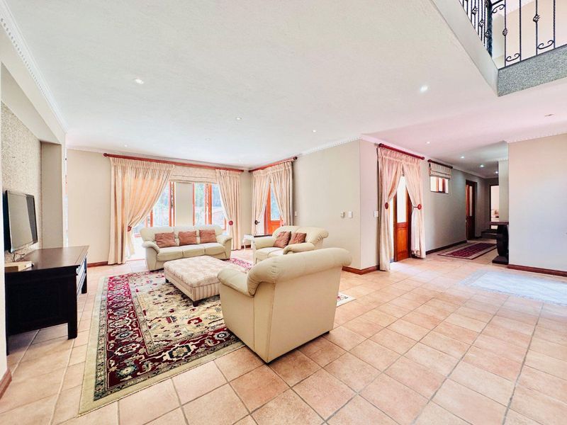 Spacious open-plan living area featuring tiled flooring, recessed downlighting, and direct access to the hallway and staircase.