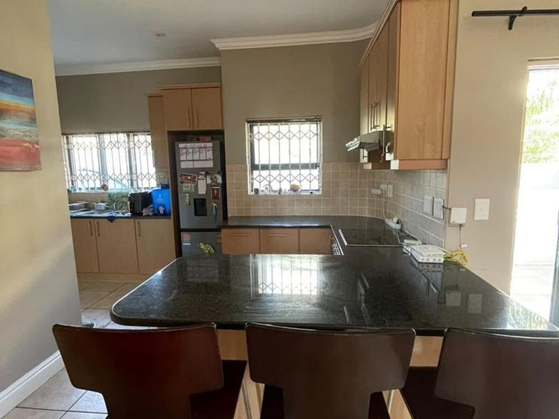 Functional kitchen featuring granite countertops, light wood cabinetry, tiled backsplash, and ceramic flooring with direct access to the outdoor area.