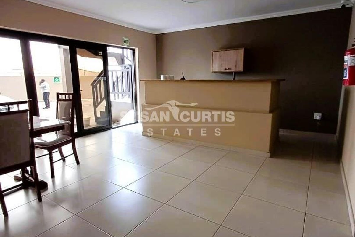 A living area featuring a built-in bar counter, tiled flooring, and sliding glass doors providing access to an outdoor space.