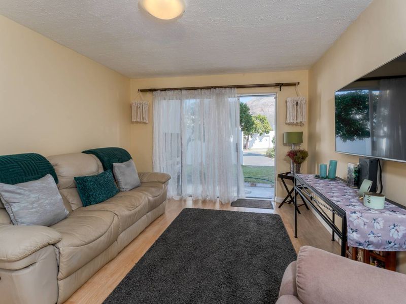 A comfortable living room featuring laminate flooring and a sliding glass door that provides direct access to the outdoor area.
