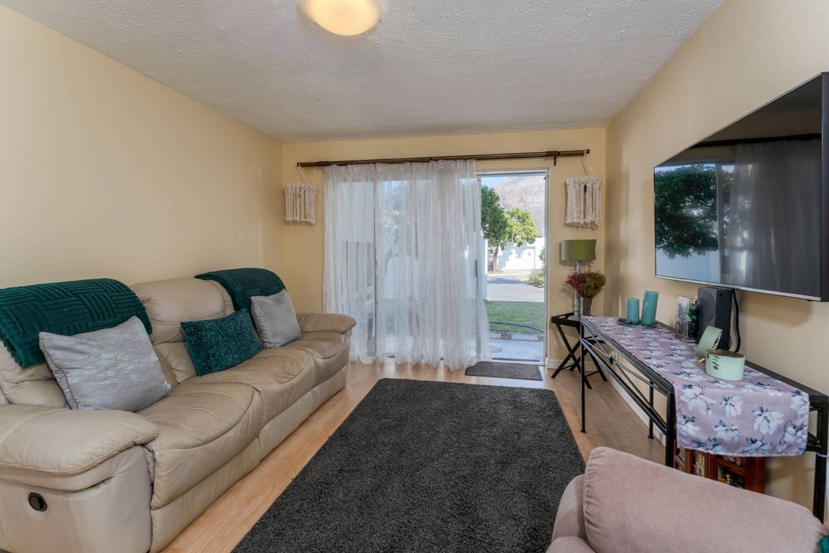A comfortable living room featuring laminate flooring and a sliding glass door that provides direct access to the outdoor area.