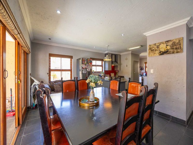 Open-plan dining area flowing into a functional kitchen, featuring tiled floors, recessed lighting, and direct access to an outdoor patio through sliding glass doors.