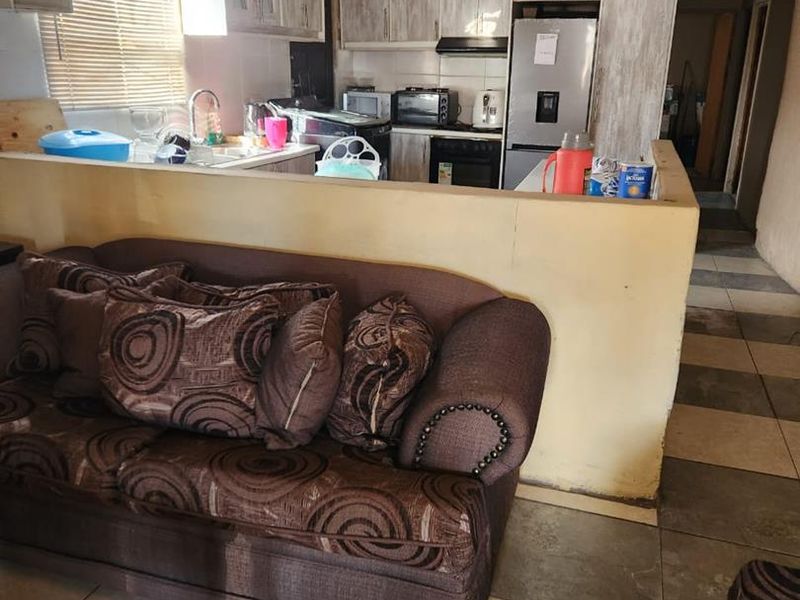 Open plan living and kitchen area featuring tiled floors and cabinetry, currently requiring significant ceiling repairs and cosmetic updates.