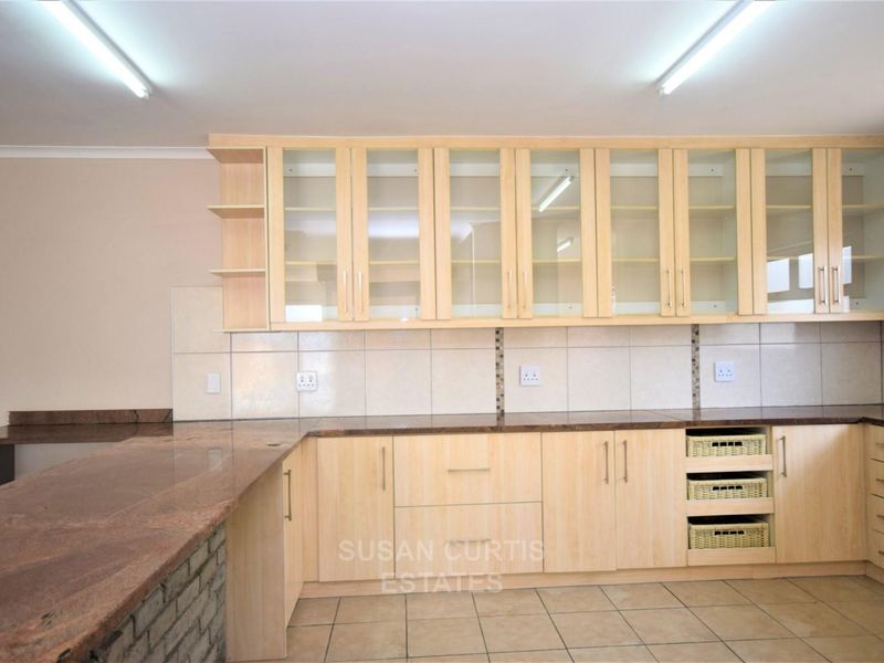 A functional kitchen featuring light wood cabinetry, granite countertops, tiled backsplash, and ample storage space, presented in a clean, empty condition.