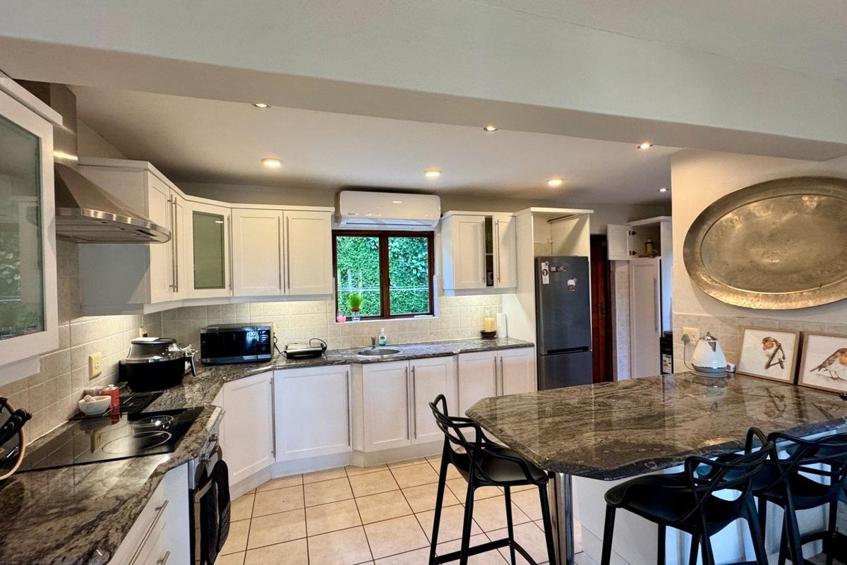 A well-appointed kitchen featuring granite countertops, white cabinetry, integrated appliances, and a breakfast bar, complemented by recessed lighting and tiled flooring.