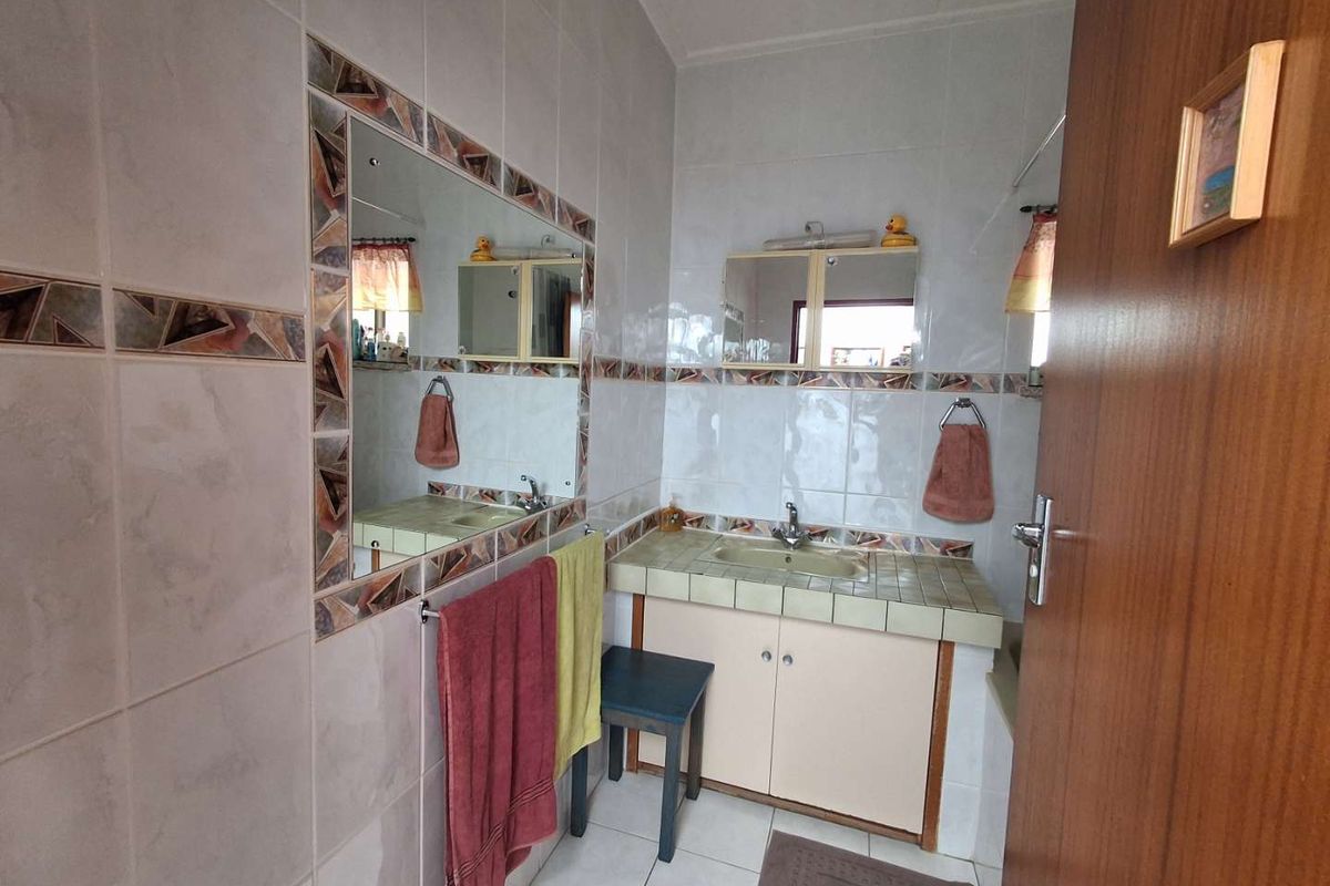 A functional bathroom featuring a tiled vanity with integrated basin, wall-mounted mirror, and full-height wall tiling.