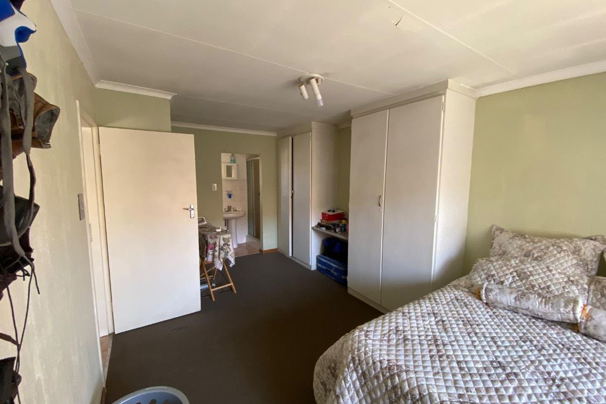 Bedroom featuring built-in cupboards and an en-suite bathroom, offering functional storage and a practical layout.