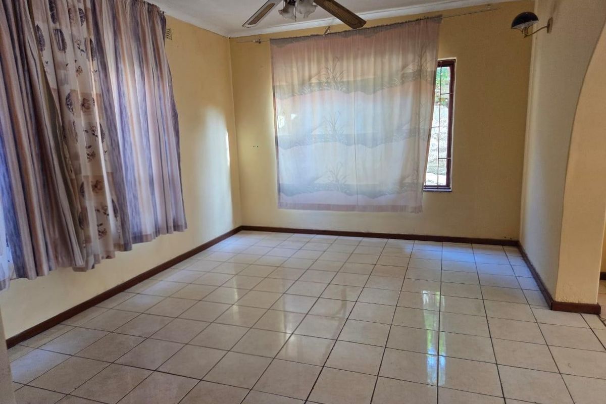 An empty living room featuring neutral wall paint, ceramic floor tiles, and a ceiling fan, offering a blank canvas for interior design.
