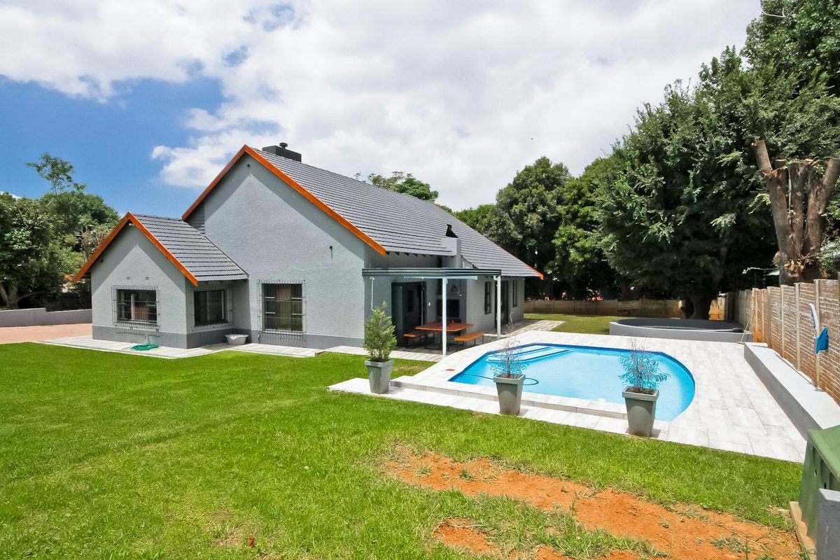 Rear view of the property featuring a well-maintained garden, a swimming pool with paved surround, and a covered patio area.