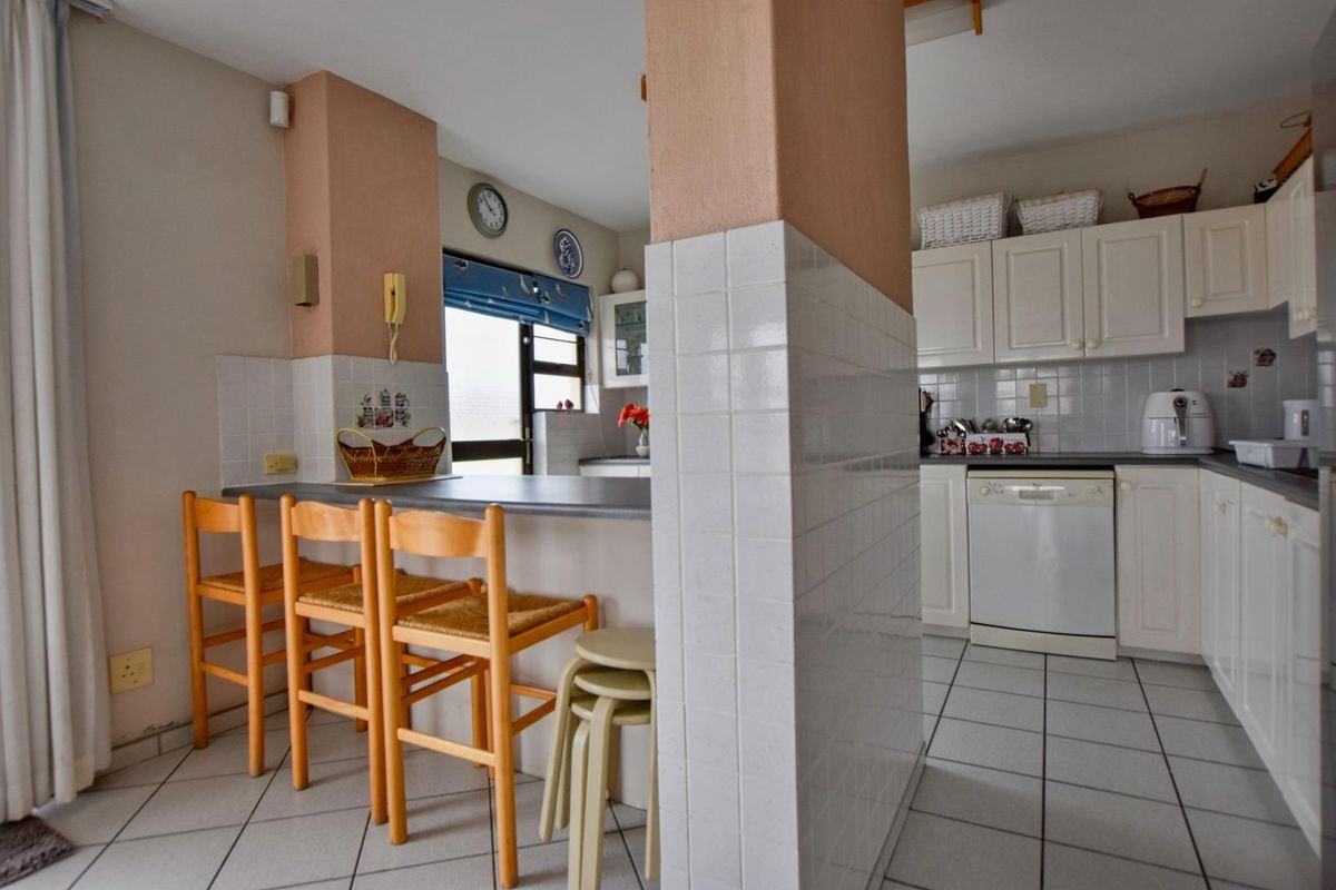A functional kitchen featuring a breakfast bar, tiled flooring, and white cabinetry, offering a practical layout for daily meal preparation.