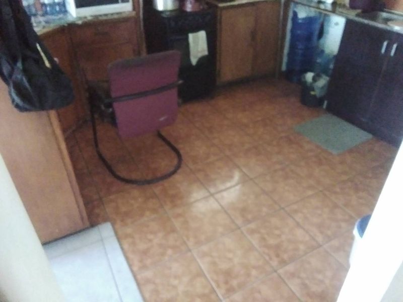 A dated kitchen area featuring tiled flooring and built-in cabinetry, requiring cosmetic updates to modernize the space.