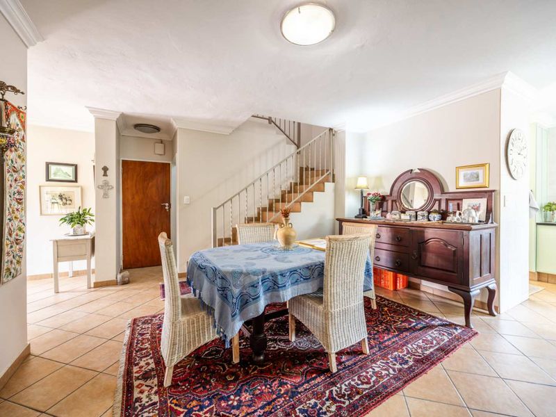 Open plan dining area featuring tiled flooring and a staircase leading to the upper level, with an adjacent kitchen visible.
