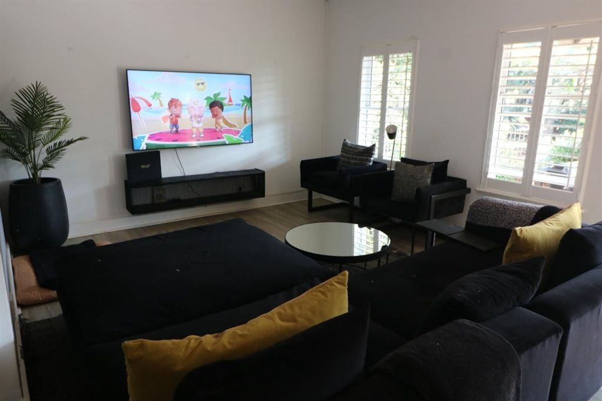 A comfortable living room featuring light-toned laminate flooring and white plantation shutters, providing a bright and neutral foundation for the space.
