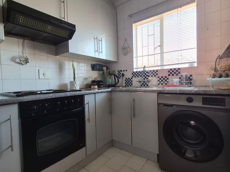 Compact kitchen featuring built-in cabinetry, integrated oven and hob, extractor fan, and tiled backsplash with a functional layout.