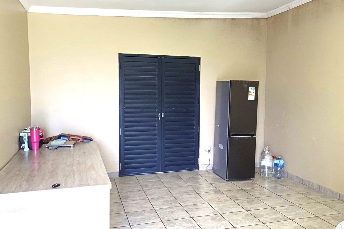 An empty living area featuring tiled flooring, coved ceiling cornices, and dark louvered double doors, requiring cosmetic wall updates.