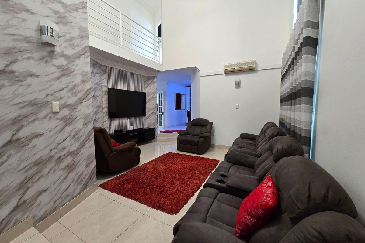 Spacious living room featuring high ceilings, a mezzanine level, tiled flooring, and decorative wall paneling with integrated air conditioning.