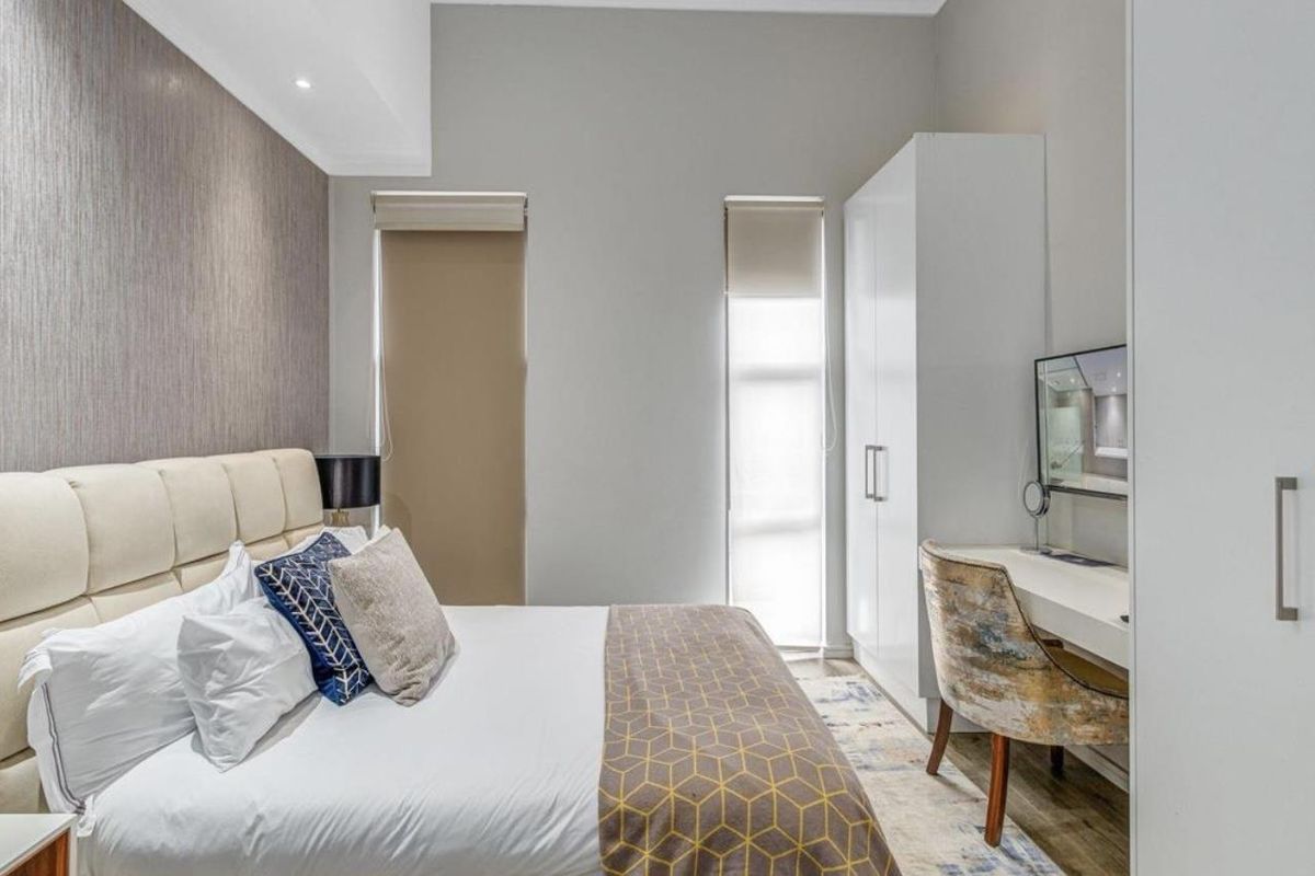 A well-maintained bedroom featuring built-in cabinetry, roller blinds, and modern recessed ceiling lighting.