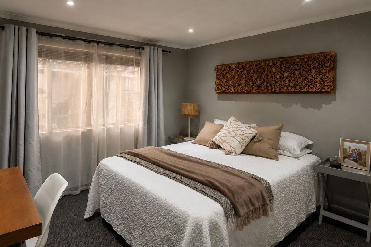 A well-maintained bedroom featuring neutral grey walls, recessed ceiling lighting, and carpeted flooring, offering a comfortable and inviting living space.
