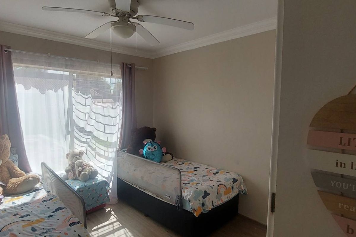 A bedroom featuring a ceiling fan, laminate flooring, and a sliding glass door providing natural light.