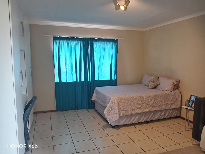 A functional bedroom featuring tiled flooring and built-in cupboards, providing a neutral space ready for personalization.