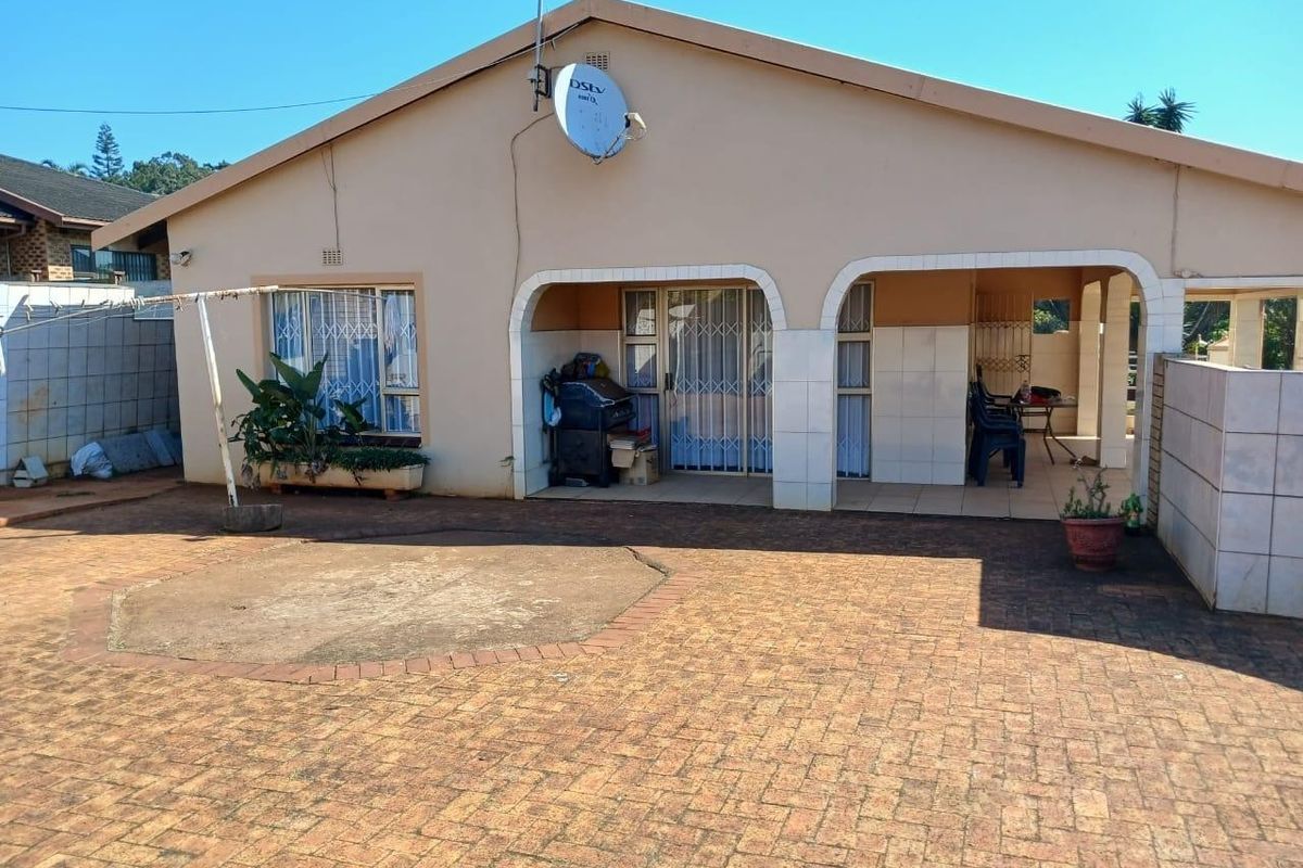 Rear view of the house featuring a covered patio area with tiled flooring and a paved courtyard space.