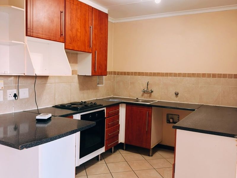 A functional kitchen space featuring built-in cabinetry, a gas hob, oven, and tiled finishes, currently requiring minor repairs and completion of cabinetry.