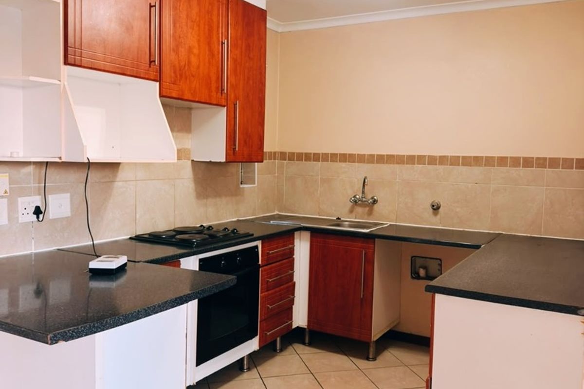 A functional kitchen space featuring built-in cabinetry, a gas hob, oven, and tiled finishes, currently requiring minor repairs and completion of cabinetry.