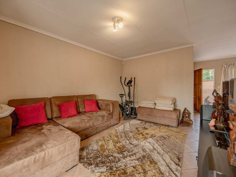 A living room area featuring tiled flooring and neutral wall finishes, providing a functional space with direct access to the exterior.