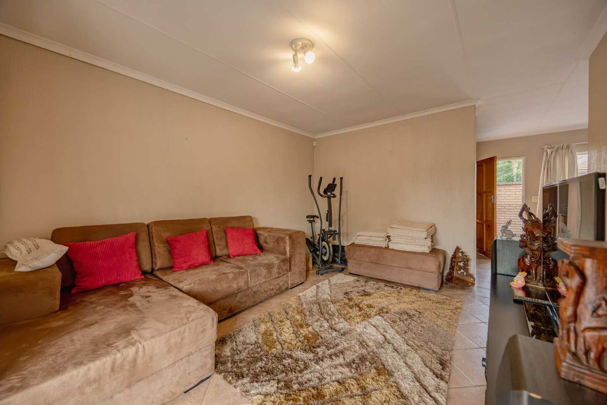A living room area featuring tiled flooring and neutral wall finishes, providing a functional space with direct access to the exterior.