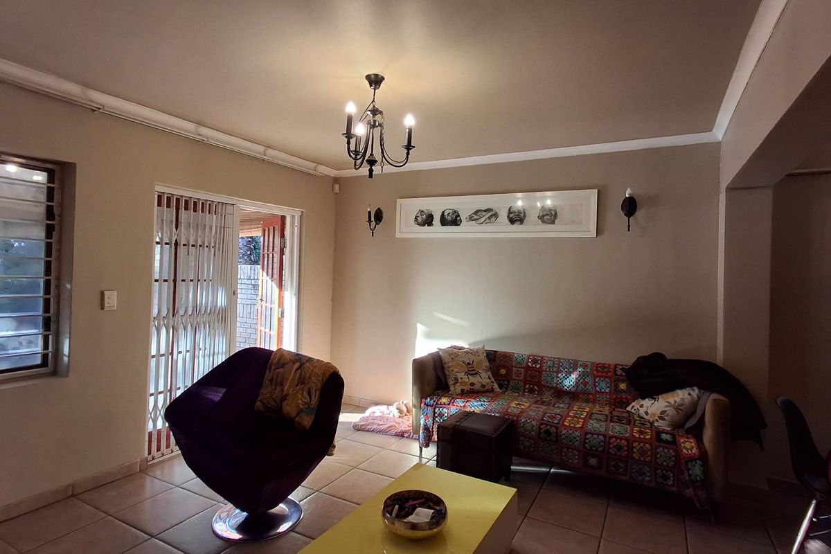 A living room featuring tiled flooring, a chandelier, and a sliding security gate leading to the exterior.