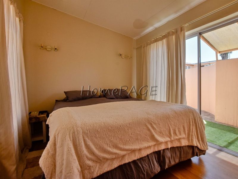 Bedroom featuring laminate flooring, wall-mounted lighting, and direct access to an outdoor patio area through sliding glass doors.