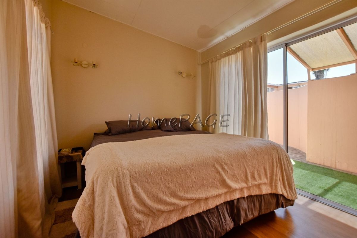 Bedroom featuring laminate flooring, wall-mounted lighting, and direct access to an outdoor patio area through sliding glass doors.