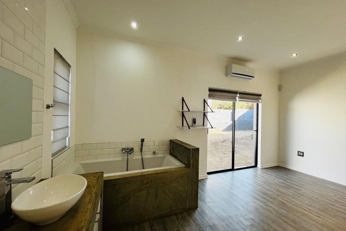 Modern bathroom featuring a built-in bathtub, vessel sink, subway tile accents, and direct access to the outdoors via a sliding glass door.
