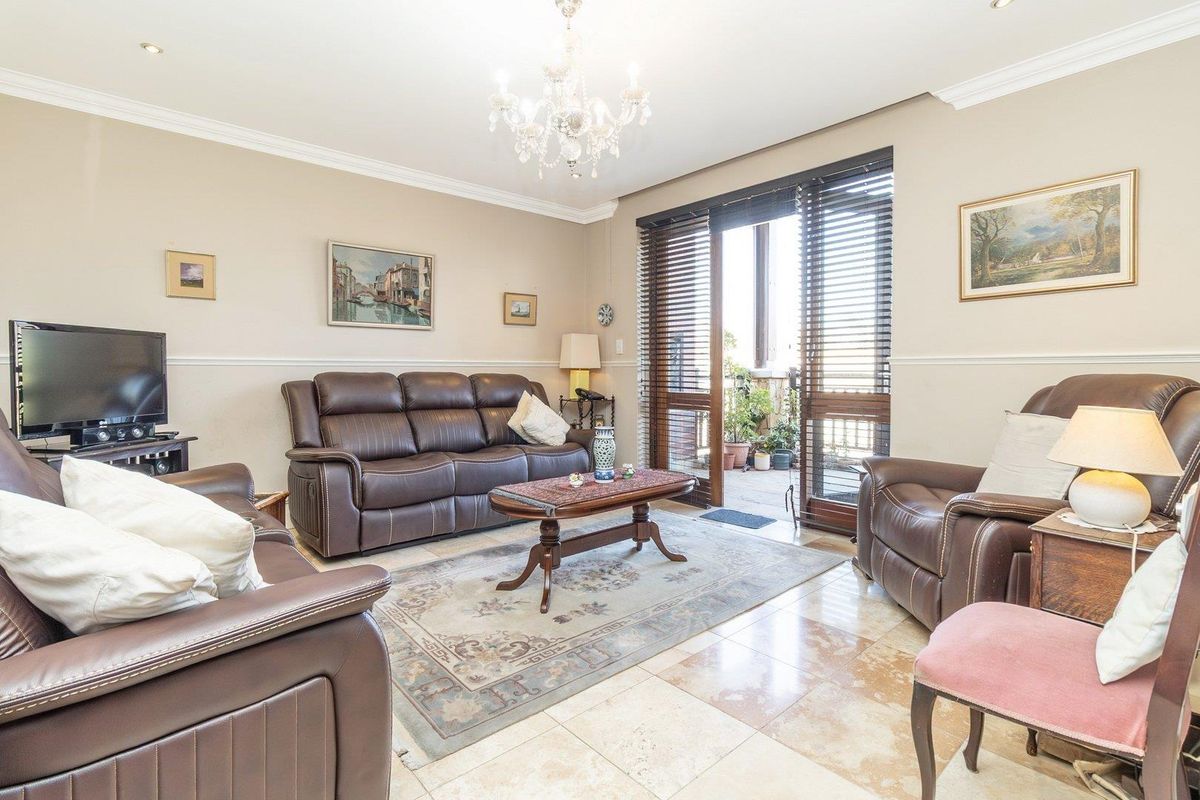 A comfortable living room featuring polished stone flooring, crown molding, and sliding glass doors that open onto a private balcony.