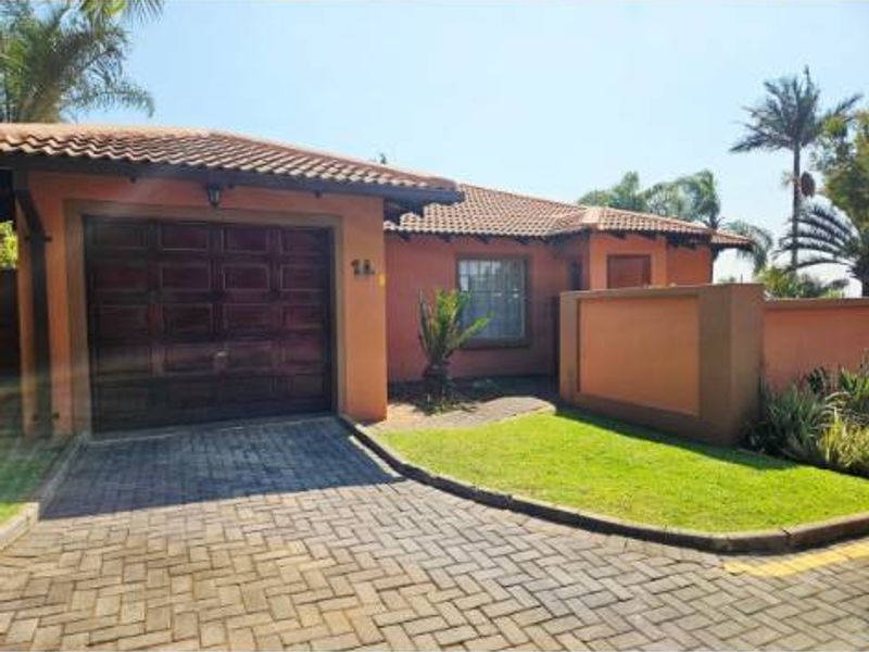 A single-story residential property featuring a terracotta tiled roof, paved driveway, integrated garage, and established garden with boundary walling.