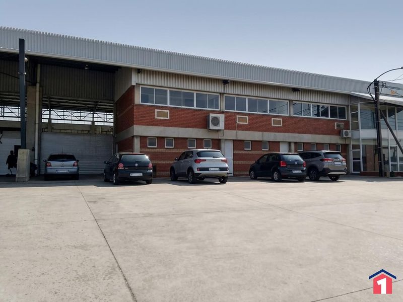 Industrial property exterior featuring a large roller shutter door, brick facade, and a spacious concrete yard area.