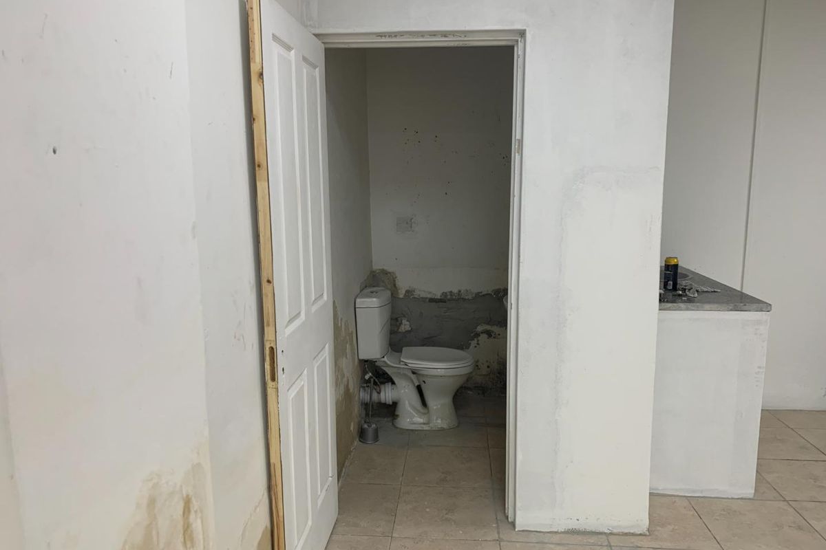 A small, unfinished office restroom featuring a standard toilet, requiring cosmetic repairs and wall finishing to restore the space.
