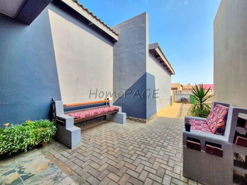 A paved outdoor patio area featuring built-in masonry seating against the exterior wall of the property.