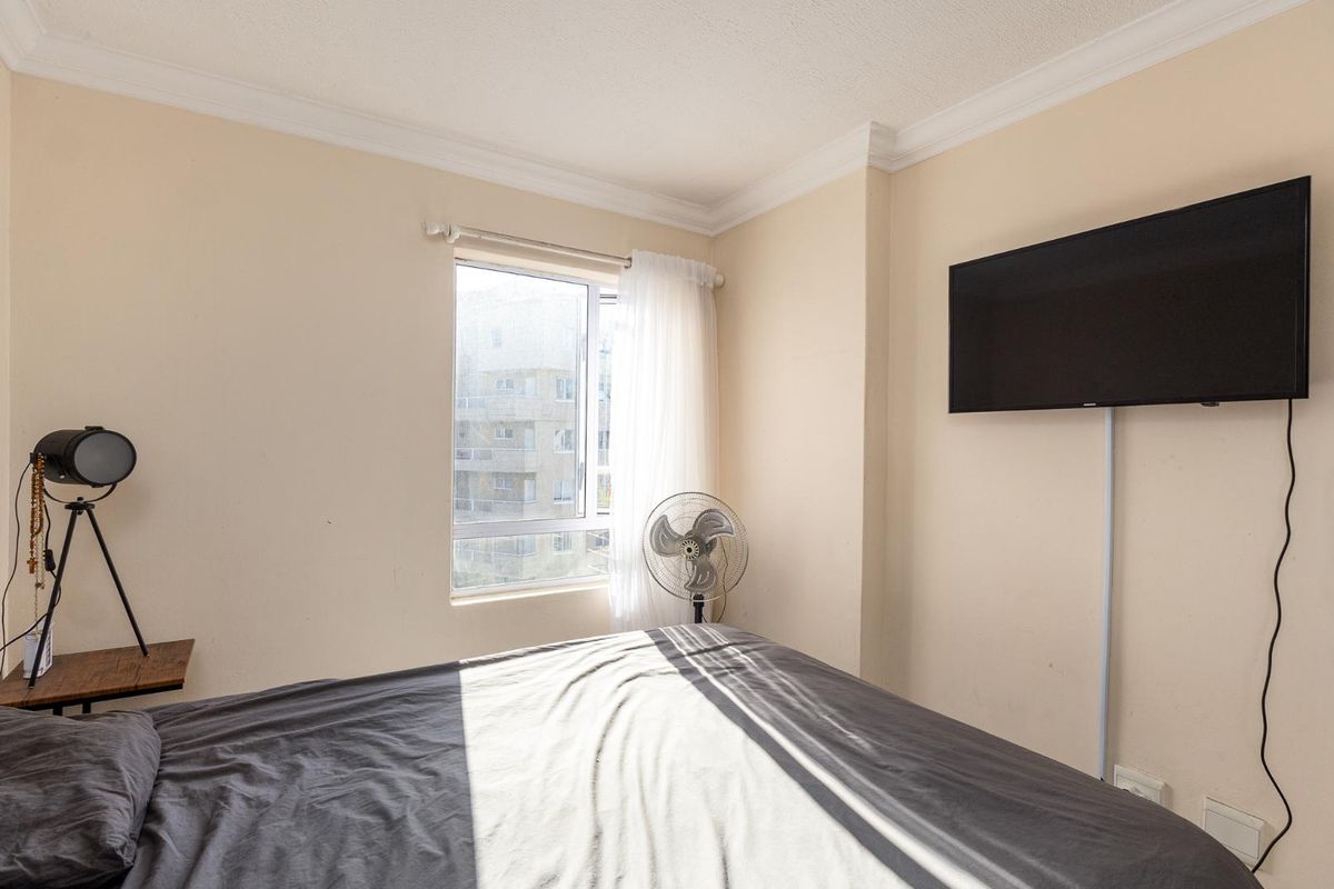 A bedroom featuring neutral walls, crown molding, and a window providing natural light.