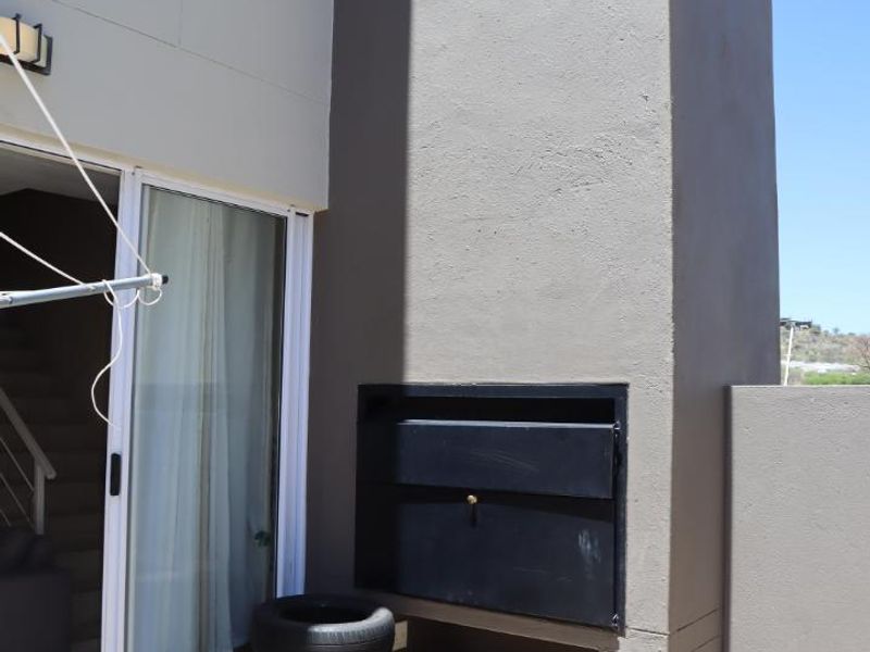Outdoor patio area featuring a built-in braai and sliding glass door access to the interior living space.