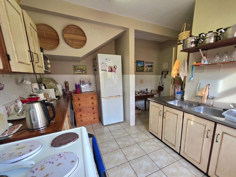 A functional kitchen featuring tiled flooring, built-in cabinetry, and a double stainless steel sink, offering a practical layout with potential for modern updates.