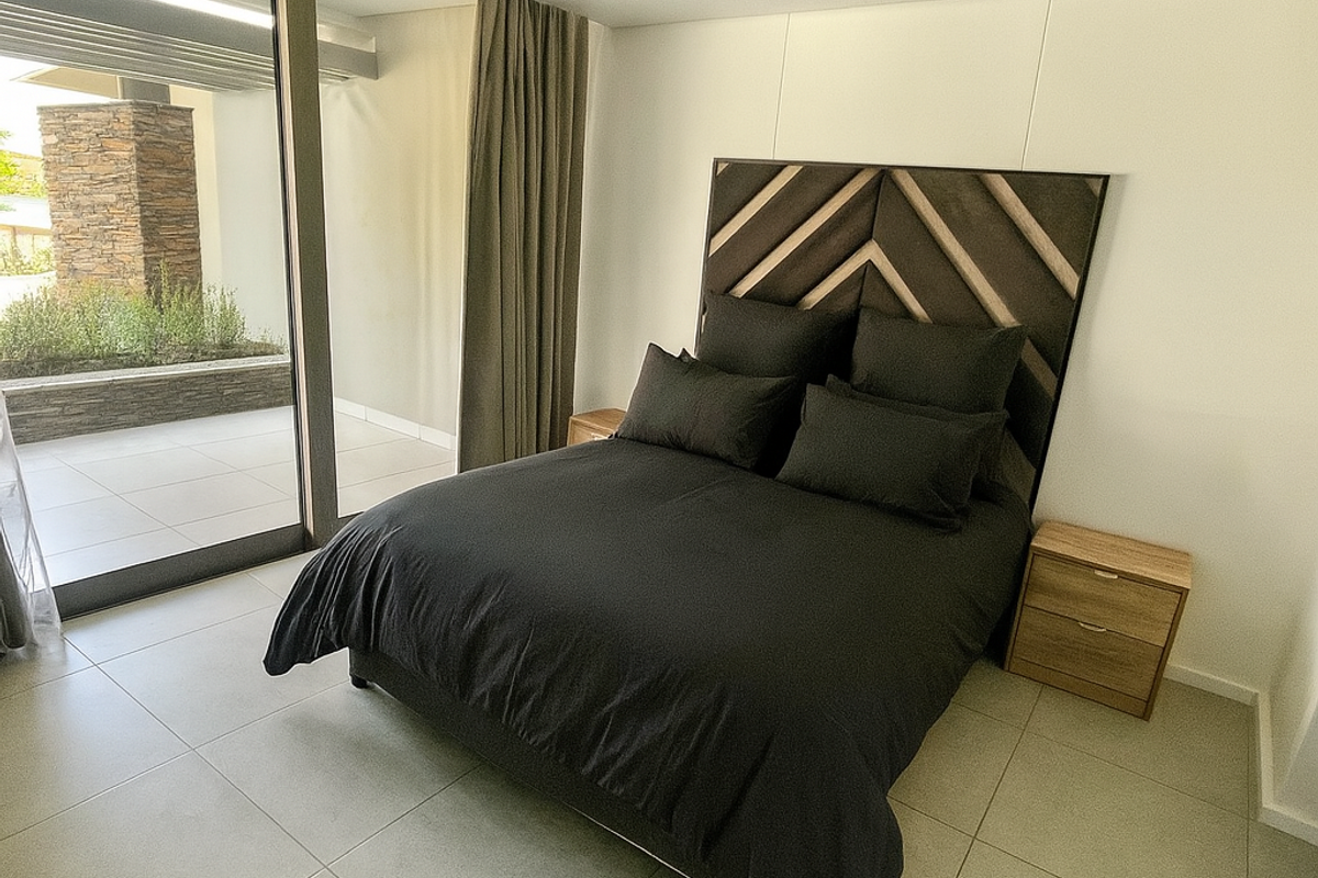 Modern bedroom featuring large floor-to-ceiling sliding glass doors that open onto a private patio area, providing excellent natural light and seamless indoor-outdoor flow.
