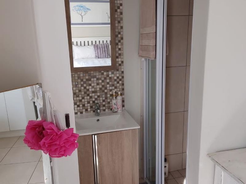 Compact bathroom featuring a vanity cabinet with basin, mosaic tile backsplash, and a separate shower enclosure with tiled flooring.