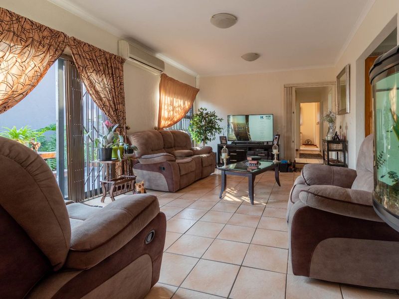 A comfortable living room featuring tiled flooring, an air conditioning unit, and a sliding glass door providing access to the outdoor area.