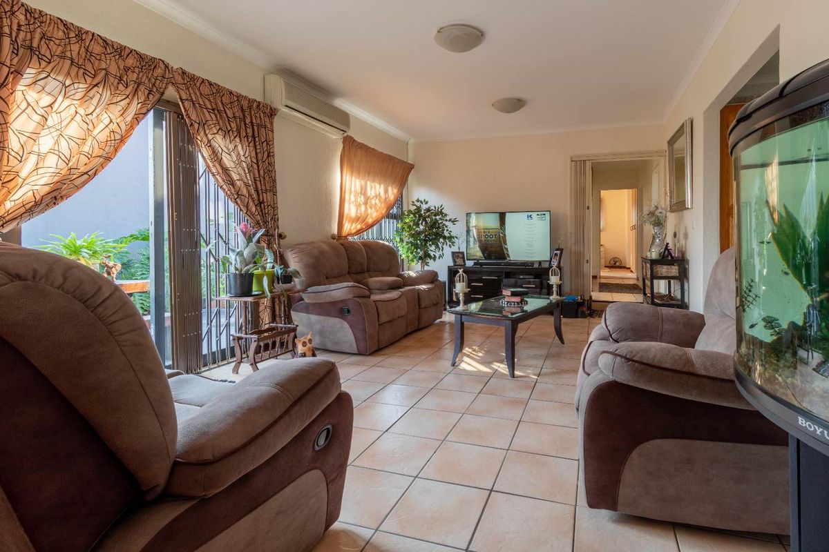 A comfortable living room featuring tiled flooring, an air conditioning unit, and a sliding glass door providing access to the outdoor area.