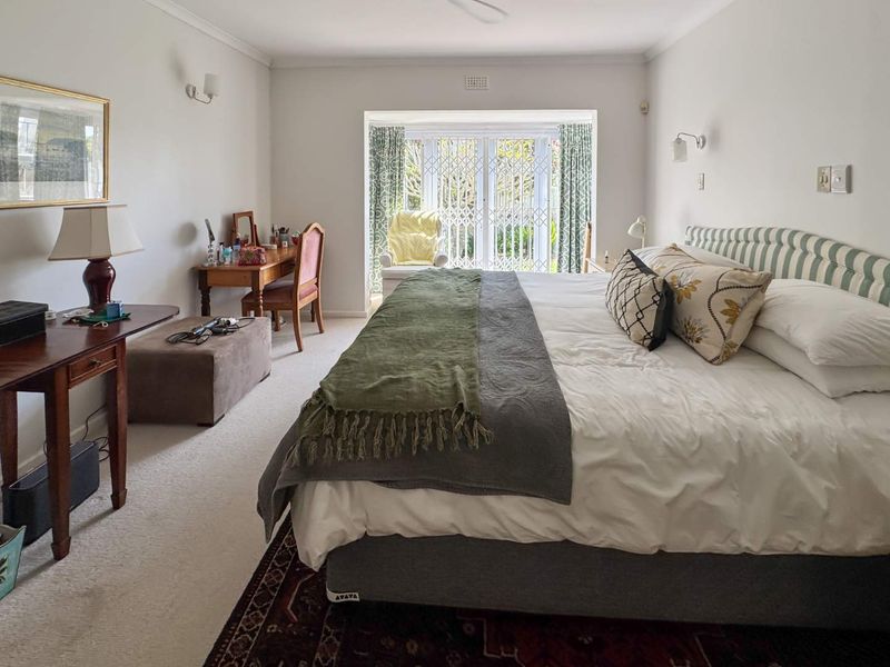 Spacious bedroom featuring neutral carpeting, wall-mounted lighting, and sliding glass doors with security gates leading to the exterior.