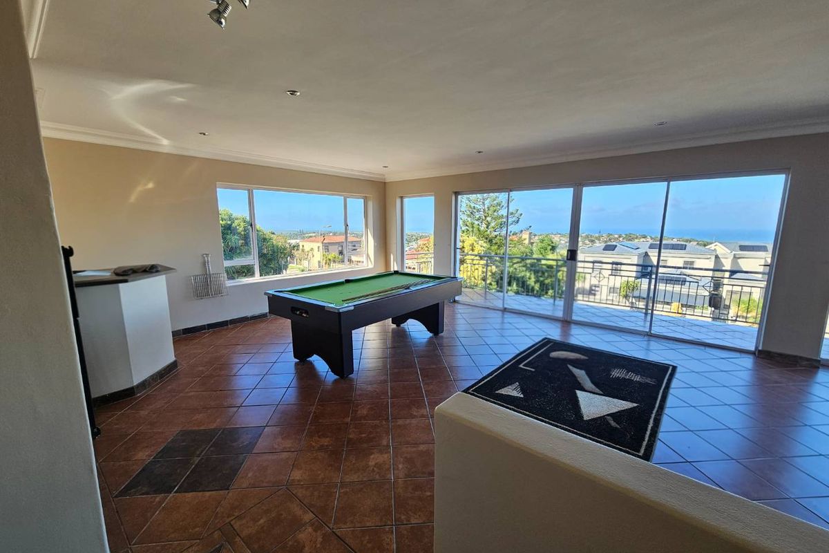 Spacious living area featuring tiled flooring, a built-in bar, and large sliding doors opening to a balcony with scenic coastal views.