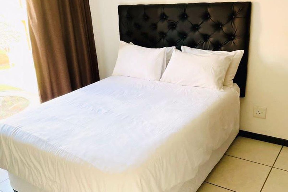 A bedroom featuring neutral tiled flooring and access to an outdoor area via a sliding door.