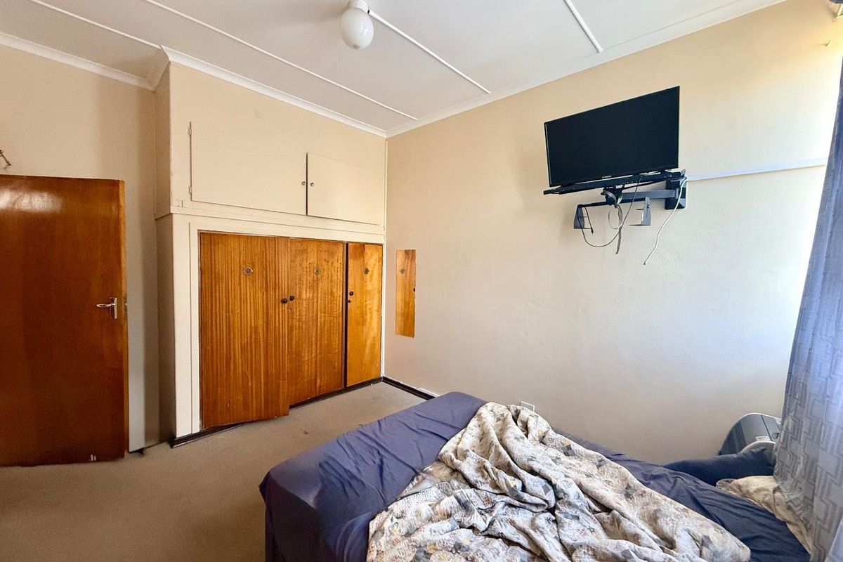 A bedroom featuring built-in wooden cupboards with overhead storage and carpeted flooring.